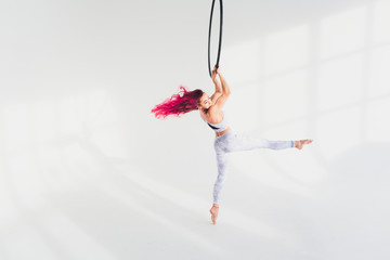 young redhead woman performs acrobatic elements in the air ring on a white background. © Евгений Вершинин