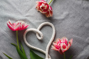 Heart from rope and bouquet of tulips on a gray background with space for text