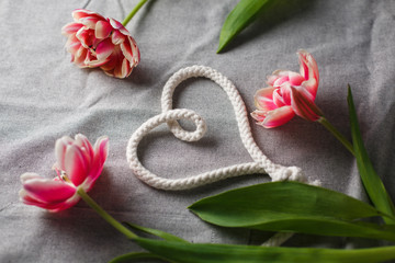 Heart from rope and bouquet of tulips on a gray background with space for text