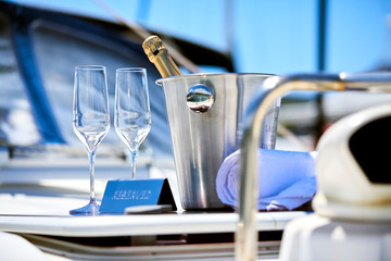 Romantic luxury evening on cruise yacht with champagne setting.Empty glasses and bottle with champagne and tropical sunset with sea background