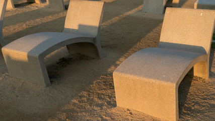 cement bench in a park with a gravel floor and the sunset light in a park