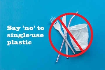 White single-use plastic and plastic drink straws on a blue background. Say no to single use plastic. Environmental, pollution concept.