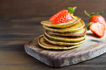 Vegetarian pancakes with ripe strawberries. on a wooden table.