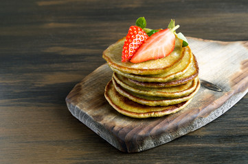 Vegetarian pancakes with ripe strawberries. on a wooden table.