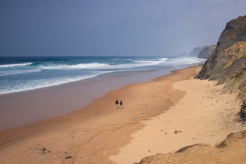 Praia da Bordeira in Carrapateira, Algarve, Portugal. Couple walking on the beach together watching the waves.