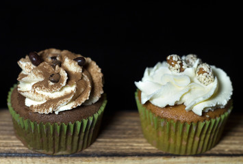 lighted cupcakes on a wooden board against a black background