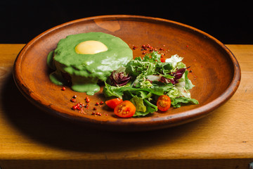 Meat with green sauce with egg on a clay plate.