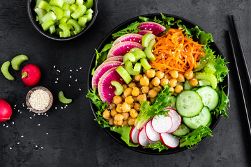Salad Buddha bowl with fresh cucumber, celery, watermelon radish, raw carrot, lettuce, radish and chickpea for lunch. Healthy vegetarian food. Vegan vegetable dish. Top view