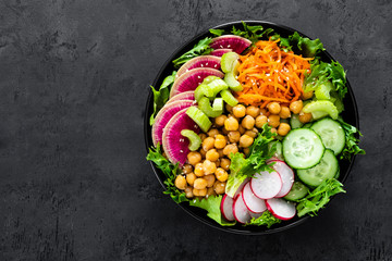 Salad Buddha bowl with fresh cucumber, celery, watermelon radish, raw carrot, lettuce, radish and...