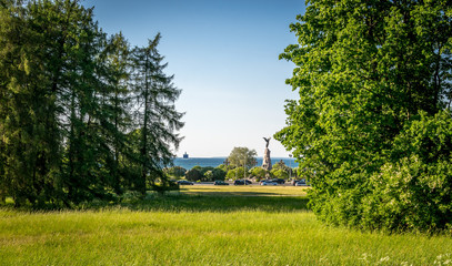 a view of the sea with a ship on the horizon and a statue. from a park. 