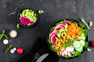 Salad Buddha bowl with fresh cucumber, celery, watermelon radish, raw carrot, lettuce, radish and chickpea for lunch. Healthy vegetarian food. Vegan vegetable dish. Top view