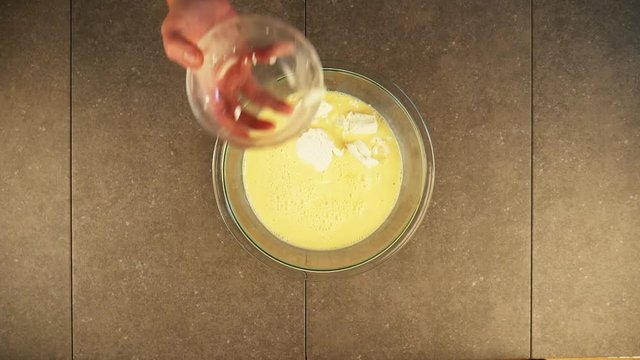 Slow motion, person adds goat cheese to frittata mixture