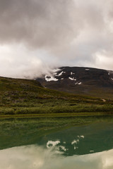 Mountain reflecting in the water in the lake at Alesjaure mountain cabin along the hike of Kungsleden (Kings trail) in northern Sweden. Shot during sunrise an early morning in summer. 