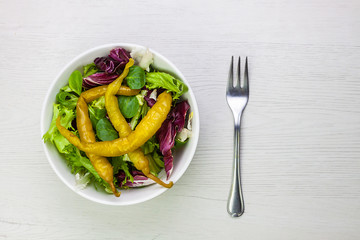 ENSALADA DE LECHUGA Y GUINDILLAS CON TENEDOR DE METAL SOBRE FONDO DE MADERA CLARA