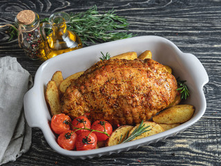 Roasted pork roulade, roll with potato and tomato in roasting pan 