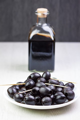 ACEITUNAS NEGRAS EN PLATO Y BOTELLA DE CRISTAL AL FONDO CON VINO DE JEREZ