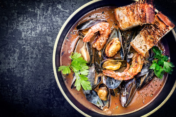Traditional French Corsican seafood stew with prawns and mussels as top view in a modern design bowl with copy space left