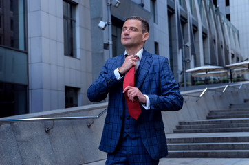 Charismatic man in a plaid suit on the background of the business center (office). Business men in...