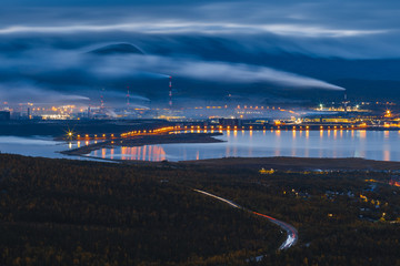 Large industrial plant at night with illumination and heavy smoke from smokestacks. Factory emitting pollution into the air. Extraction of ores and non-ferrous metallurgy. Monchegorsk, Russia
