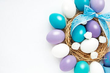 azure, purple, pastel colored Easter eggs in nest on white background, selective focus image. Happy Easter card 