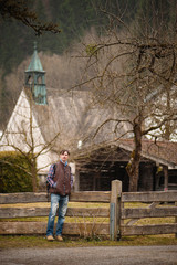 A man on the background of the house and a wooden fence