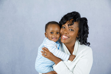 Beautiful African Amercian Woman wHolding Her Baby boy on a Gray Background - Powered by Adobe