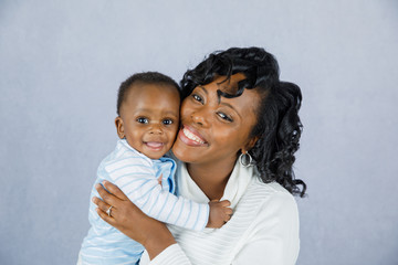 Beautiful African Amercian Woman Holding Her Baby boy on a Gray Background