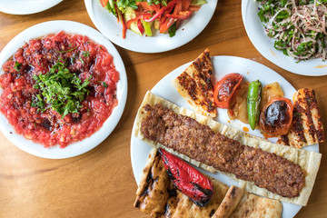 Traditional Turkish Kebab or kebap food  on plate with salads in the kebab restaurant. Skewering bbq Kebab. Traditional Turkish Adana Kebab
