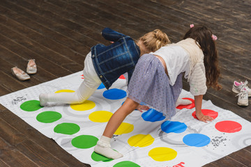 Two children playing twister on the floor