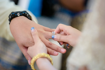 Wedding rings.She Put the Wedding Ring on Him.Close up bride Put the Ring on Groom. thai wedding ceremony and thai wedding decoration.