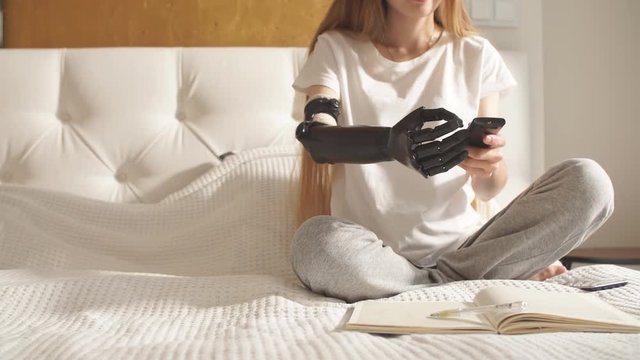 Girl with a prosthetic arm holding remote control. Disabled girl tries to hold a control panel