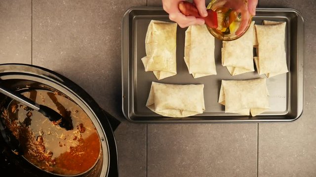 Person basting chicken burritos