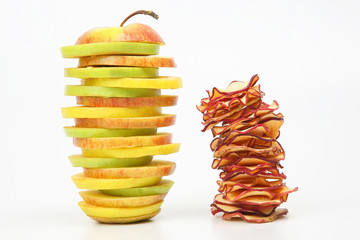 pieces of fresh and dried apples stacked in a pyramid on a white background