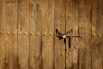 old brown wooden door with a rusty bolt and a chain with padlock