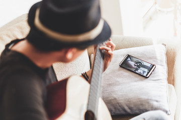 Young asian man playing spanish guitar indoors.