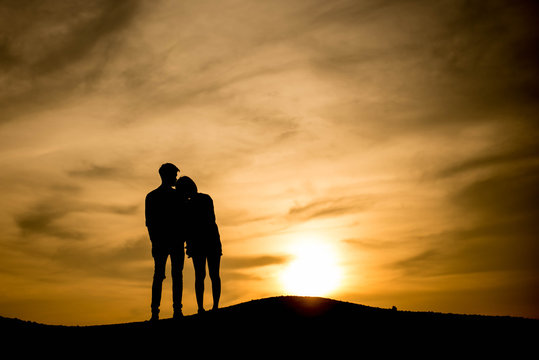 Silhouette Young man and woman on the mound At sunset