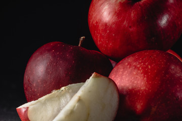 Fototapeta na wymiar Red apples and slices of apples. Dark. Baton background. Photo in low key