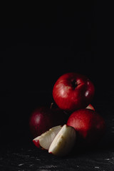 Red apples and slices of apples. Dark. Baton background. Photo in low key. Place fot text, copy paste space