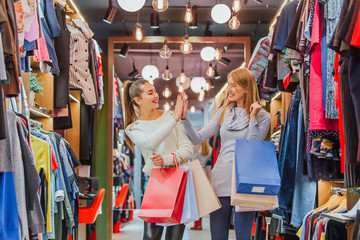 Young girls buying a lot of things in the store keep shopping bags.