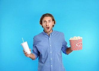 Fototapeta premium Emotional man with popcorn and beverage during cinema show on color background