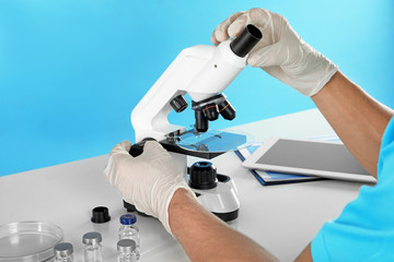 Male doctor using microscope at table, closeup. Medical object