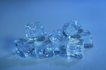 Pile of crystal clear ice cubes on color background
