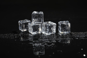 Pile of crystal clear ice cubes on black background