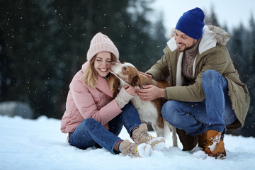 Fototapeta premium Cute couple with dog near forest. Winter vacation