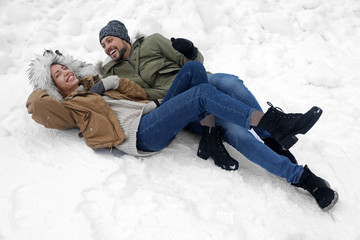 Fototapeta na wymiar Happy couple lying on snow outdoors. Winter vacation