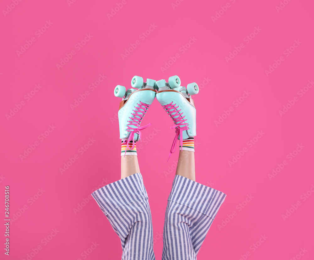 Wall mural Young woman with retro roller skates on color background, closeup