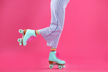 Young woman with retro roller skates on color background, closeup