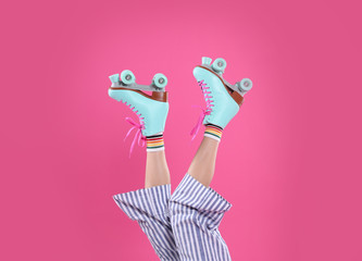 Young woman with retro roller skates on color background, closeup
