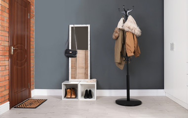 Modern hallway interior with mirror and clothes on hanger stand