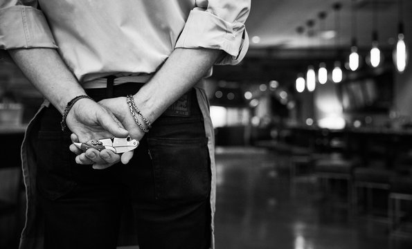 Midsection of waiter holding corkscrew in restaurant